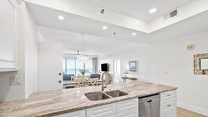 A modern kitchen with a marble countertop, double sink, and built-in dishwasher.