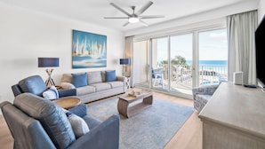 A modern living room with a sofa, coffee table, and a view of the sea through large windows.