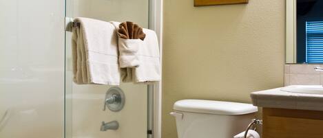 Une salle de bain avec une douche à parois de verre, des toilettes, un lavabo et un meuble en bois.