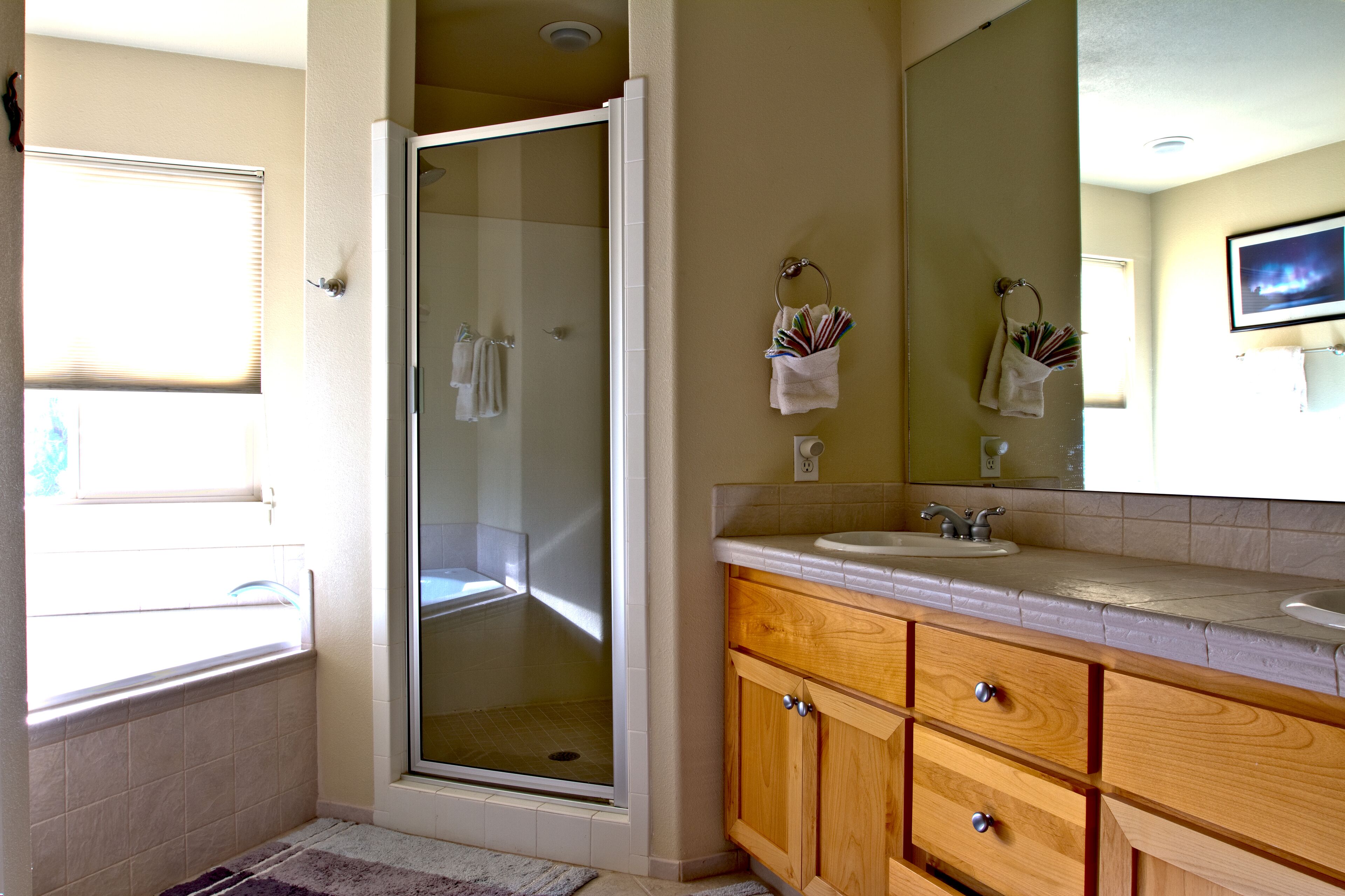 A bathroom with a glass-enclosed shower, wooden vanity, and a large mirror.