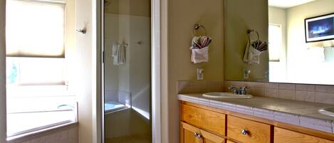 A bathroom with a glass-enclosed shower, wooden vanity, and a large mirror.