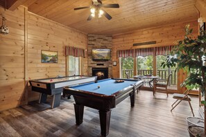 Ein Holzinnenraum mit Pooltisch, Fernseher und Kamin.