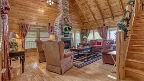 L’intérieur d’un chalet confortable, avec un foyer en pierre, des meubles en bois et un plafond haut.