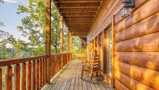 Une véranda en bois avec une balustrade, une chaise berçante et une lanterne.