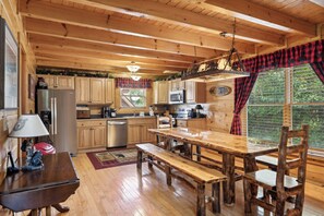A wooden cabin kitchen with a wooden table, benches, and a refrigerator.