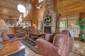 Un interior de cabaña acogedor con chimenea de piedra, techo de madera y asientos cómodos.