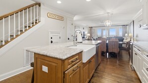 Una cucina con mobili in legno, un piano di lavoro in granito e un cartello con la scritta 'BEACH HOUSE'.