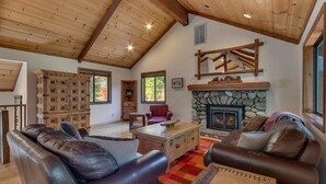 A cozy living room with leather sofas, a stone fireplace, and wooden beams on the ceiling.