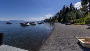 A pebble beach with boats docked and a wooden deck.