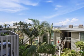 Un quartier résidentiel offrant une vue sur l’océan, avec un escalier menant à un balcon et un bâtiment doté d’une façade en pierre.