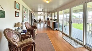 A spacious living area with a kitchen, large sliding glass doors leading to a deck, and a view of the backyard.