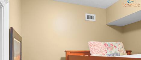 A bedroom with a wooden bunk bed, a framed picture on the wall, and a flat-screen TV displaying 'Legacy Vacations'.