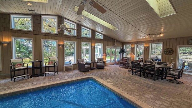 A spacious indoor pool area with multiple seating arrangements and large windows providing natural light. - Newmans Beachview 3 bedrooms, 3 bathrooms (Jekyll Island)