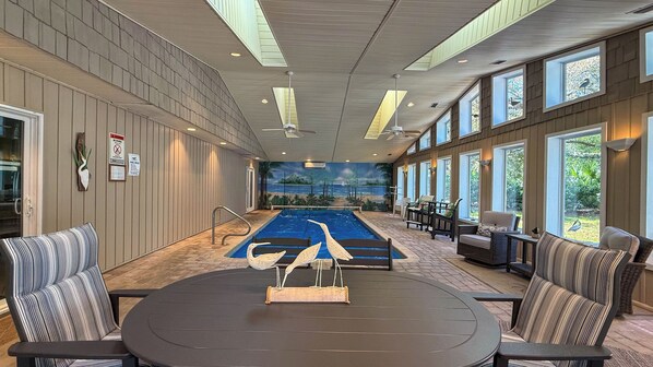 A pool area with a mural, seating, and a view of the outdoors.