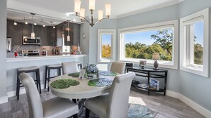 Une cuisine moderne avec des meubles de couleur sombre, un four à micro-ondes et une cuisinière. On y trouve également un coin repas avec une table, des chaises et un lustre.