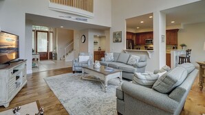 A spacious living room with a high ceiling, a staircase, and a kitchen area visible through an open doorway. - 69 Shell Ring - Nestled in A Quiet Sea Pines Community offering Pool & Tennis (Hilton Head Island)