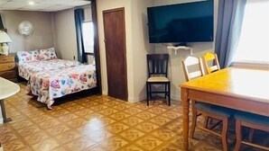 Una stanza con un letto, una TV, un tavolo da pranzo e una sedia.