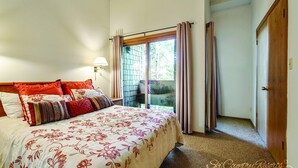 Un dormitorio con una cama grande, una ventana con cortinas y una puerta.