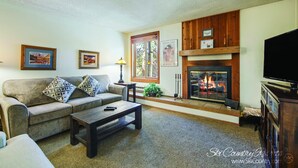 Una sala de estar con chimenea, sofá, mesa de centro y televisor.