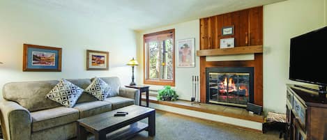 A living room with a fireplace, a sofa, a coffee table, and a television.
