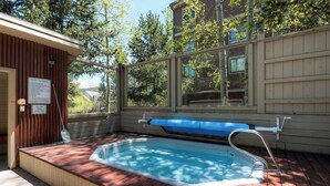Un jacuzzi con muelle de madera y ventana con vista a un área boscosa.