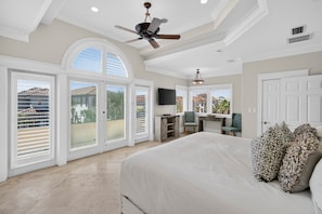 A spacious bedroom with a large bed, a ceiling fan, and a view of the outside through the sliding glass doors. - Costa Del Mar - Steps from Private Beach Access with Ocean View & Private Pool! (Destin)