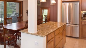 Una cocina con armarios de madera, un refrigerador de acero inoxidable y una encimera de granito.
