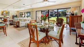A spacious living area with a dining table set for four, surrounded by wicker chairs. - Ma'alaea Surf, Unit G5-1 Bd Beachfront Condo, AC, Wi-Fi, TV, Kitchen, Pool (Kihei)