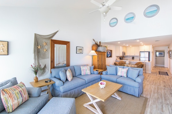 A modern living room with a sectional sofa, a wooden coffee table, and a ceiling fan.