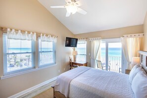 A bedroom with a bed, a television, a desk with a chair, and a view of the ocean through the windows. - Whispering Sands #301 - Gulf Front Condo on Private Dune Allen Beach! (Santa Rosa Beach)