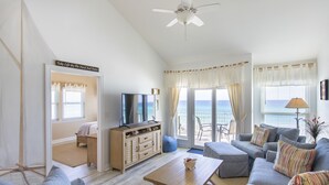 A spacious living room with a large sofa set, a coffee table, and a television. There is a view of the ocean through the windows. - Gulf Front Condo, 3rd level, Amazing Views - Near shops/restaurants (Santa Rosa Beach)