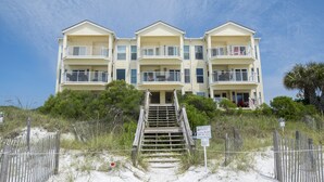 A beachfront hotel with multiple balconies, a sandy beach in front, and a wooden fence. - Gulf Front Condo, 3rd level, Amazing Views - Near shops/restaurants (Santa Rosa Beach)