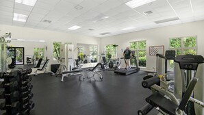 A gym with various exercise equipment, large windows, and a clean, well-lit interior. - Luxurious Ground Floor Condo: Proximity to Pool, Full Access to Amenities. (Herradura)
