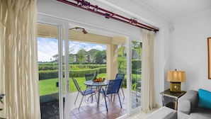 A room with a sliding glass door leading to a patio with a table and chairs, a lamp, and a sofa. - Luxurious Ground Floor Condo: Proximity to Pool, Full Access to Amenities. (Herradura)