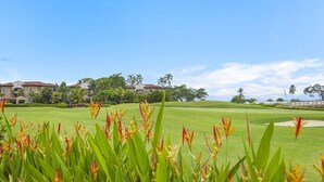 A golf course with well-manicured grass, palm trees, and a clear blue sky. - Luxurious Ground Floor Condo: Proximity to Pool, Full Access to Amenities. (Herradura)