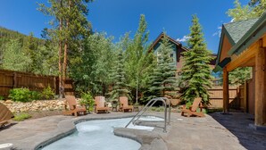 Un espace avec un jacuzzi, doté d’une terrasse en bois, entouré d’arbres et délimité par une clôture en bois.
