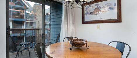 A dining area with a wooden table, black chairs, a woven basket, and a chandelier.