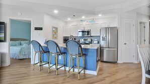 A modern kitchen with a central island, stainless steel appliances, and a blue accent wall. - Sea Crest 2509 - Beautiful 5th Floor Condo with Breathtaking Ocean Views! (Hilton Head Island)
