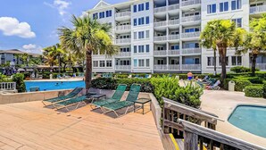 A hotel with a pool area, lounge chairs, and a wooden deck. - Sea Crest 2509 - Beautiful 5th Floor Condo with Breathtaking Ocean Views! (Hilton Head Island)