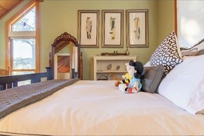 A bedroom with a large bed, a wooden headboard, a fireplace, and framed artwork on the wall. - Captivating Muir Beach Home With Sweeping Views and Fast/Stable Wireless Wifi (Muir Beach)