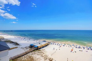 A beach with a pier, beach umbrellas, and a lifeguard tower.