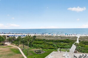 A beach view with a path leading to a patio area with outdoor seating. - First Light at Coligny Panoramic Oceanfront Retreat • Newly Updated Condo (Hilton Head Island)