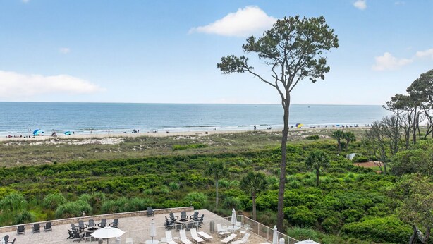 Vista de la playa con un área de patio que incluye asientos exteriores y sombrillas.