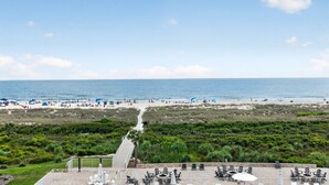 Vista de una playa con un camino que lleva a un patio amoblado al aire libre.