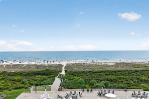 Une vue sur la plage avec un sentier menant à un patio doté de sièges extérieurs.