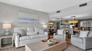Una sala de estar moderna con sofá, sillones, una mesa de centro y un comedor con candelabro.