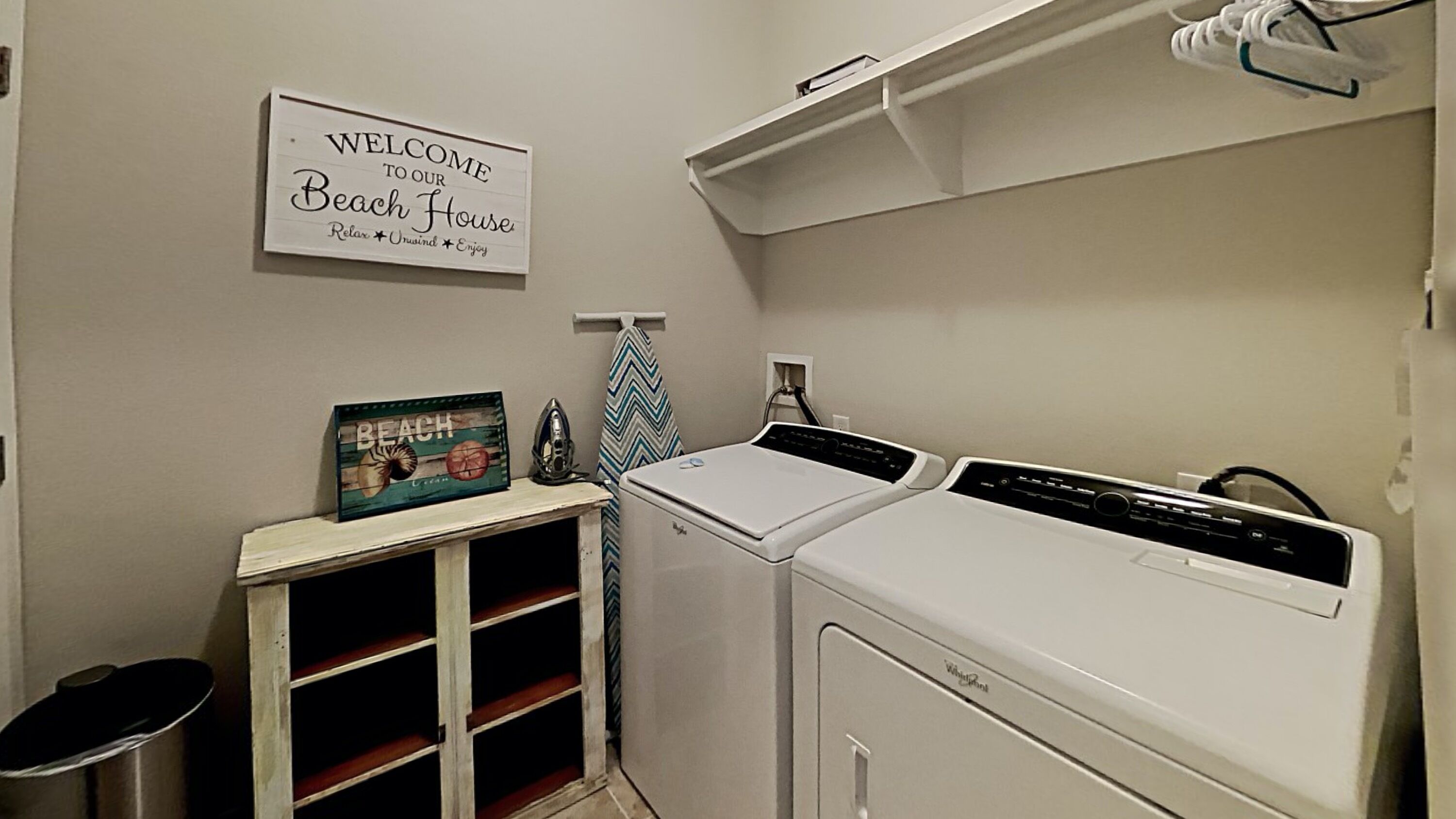 A laundry room with a sign reading 'Welcome to our Beach House Relax Unsigned Enjoy.'