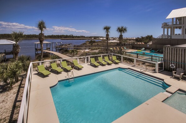 A pool area with lounge chairs, a pool, and a view of the water. - Seaspray 7bed7.5B, Grayton, pool,Gulf /Lake view,DOCK,playroom!Red Bar! (Santa Rosa Beach)