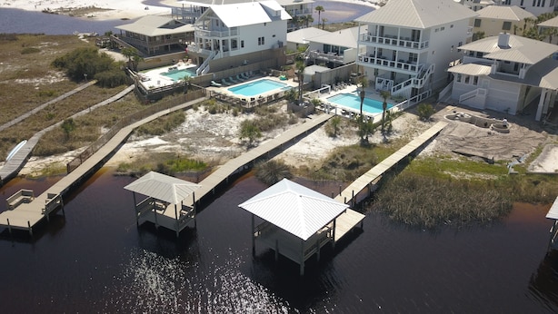A coastal hotel with multiple buildings, a swimming pool, and a dock area. - Seaspray 7bed7.5B, Grayton, pool,Gulf /Lake view,DOCK,playroom!Red Bar! (Santa Rosa Beach)