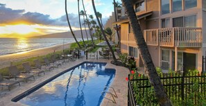 A hotel with a pool, beach view, and palm trees.
